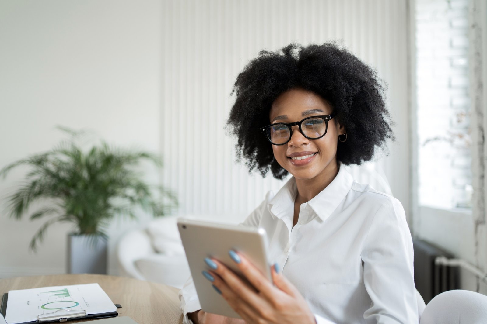 A female secretary makes an online report to the workplace in the office, uses a tablet